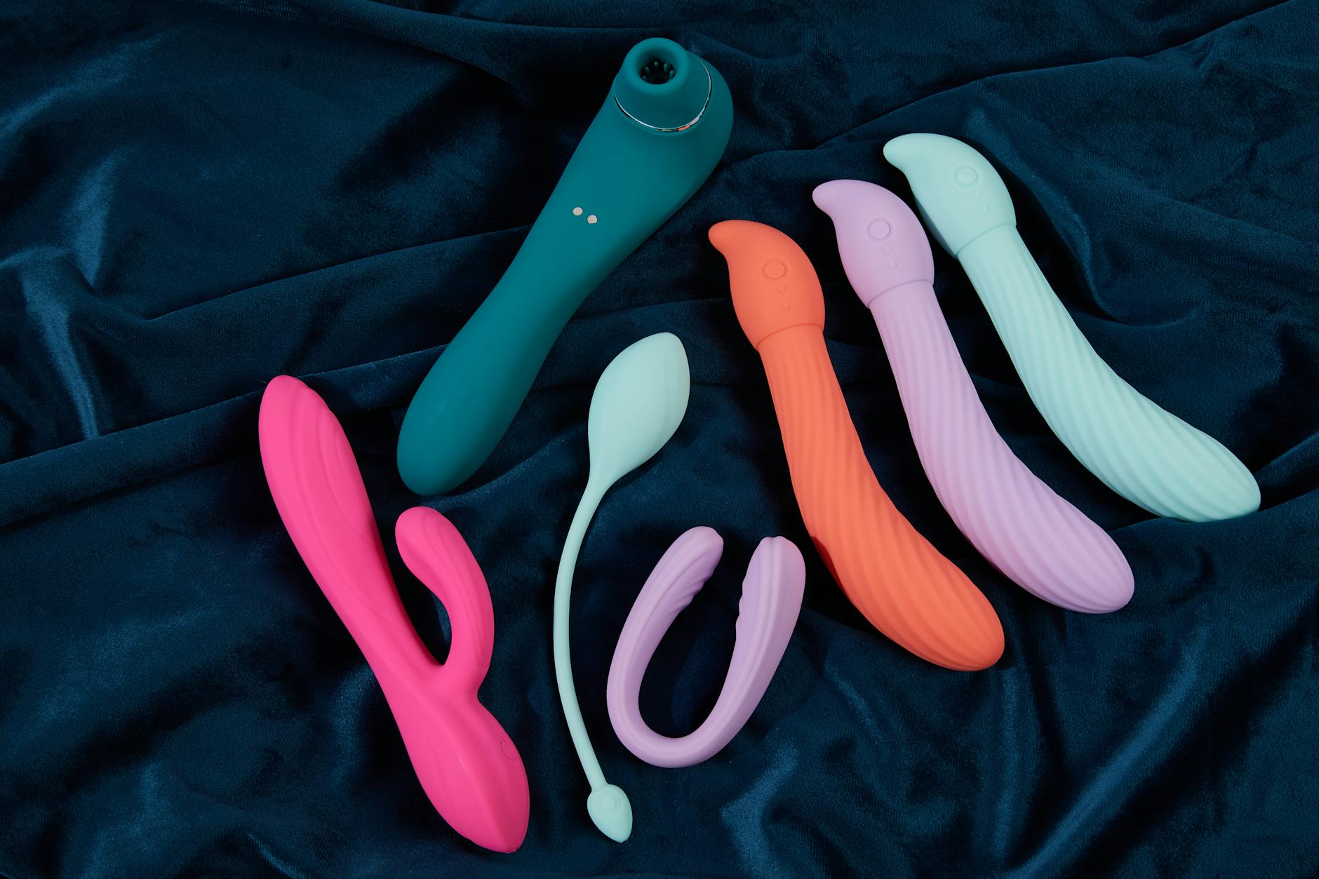 Vibrant display of silicone lemon vibrators and clitoral toys arranged on dark blue fabric.