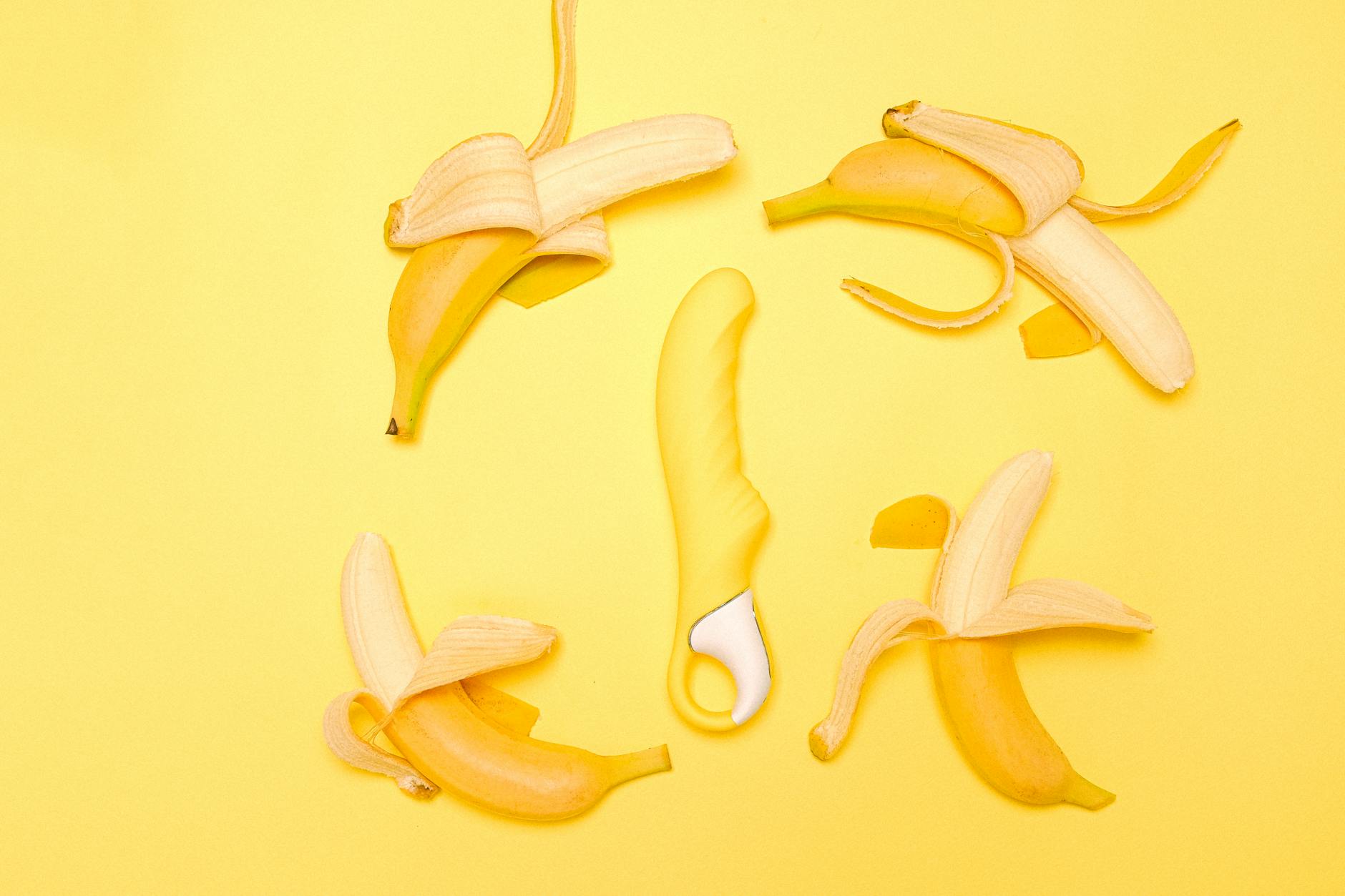 Un vibromasseur citron jaune silicone entouré de citrons frais sur fond jaune vif