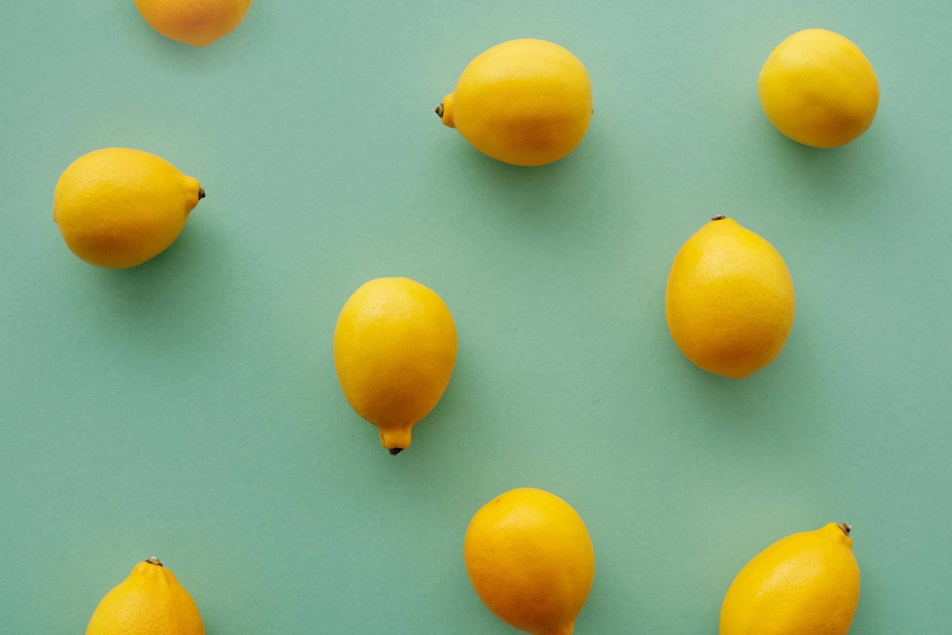Bright yellow lemons arranged on a pastel green background, symbolizing fresh approaches to pleasure after hormonal changes
