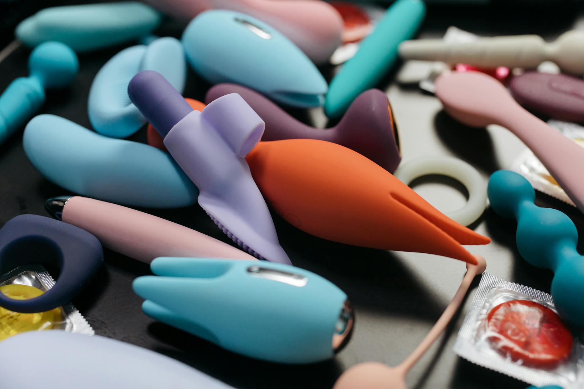 Woman holding two colorful vibrators thoughtfully
