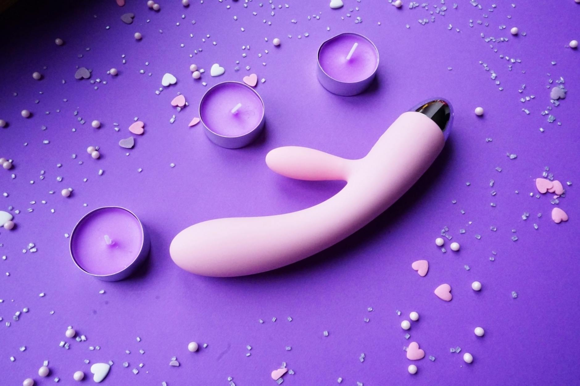 Yellow silicone lemon vibrator surrounded by fresh lemons on a bright background