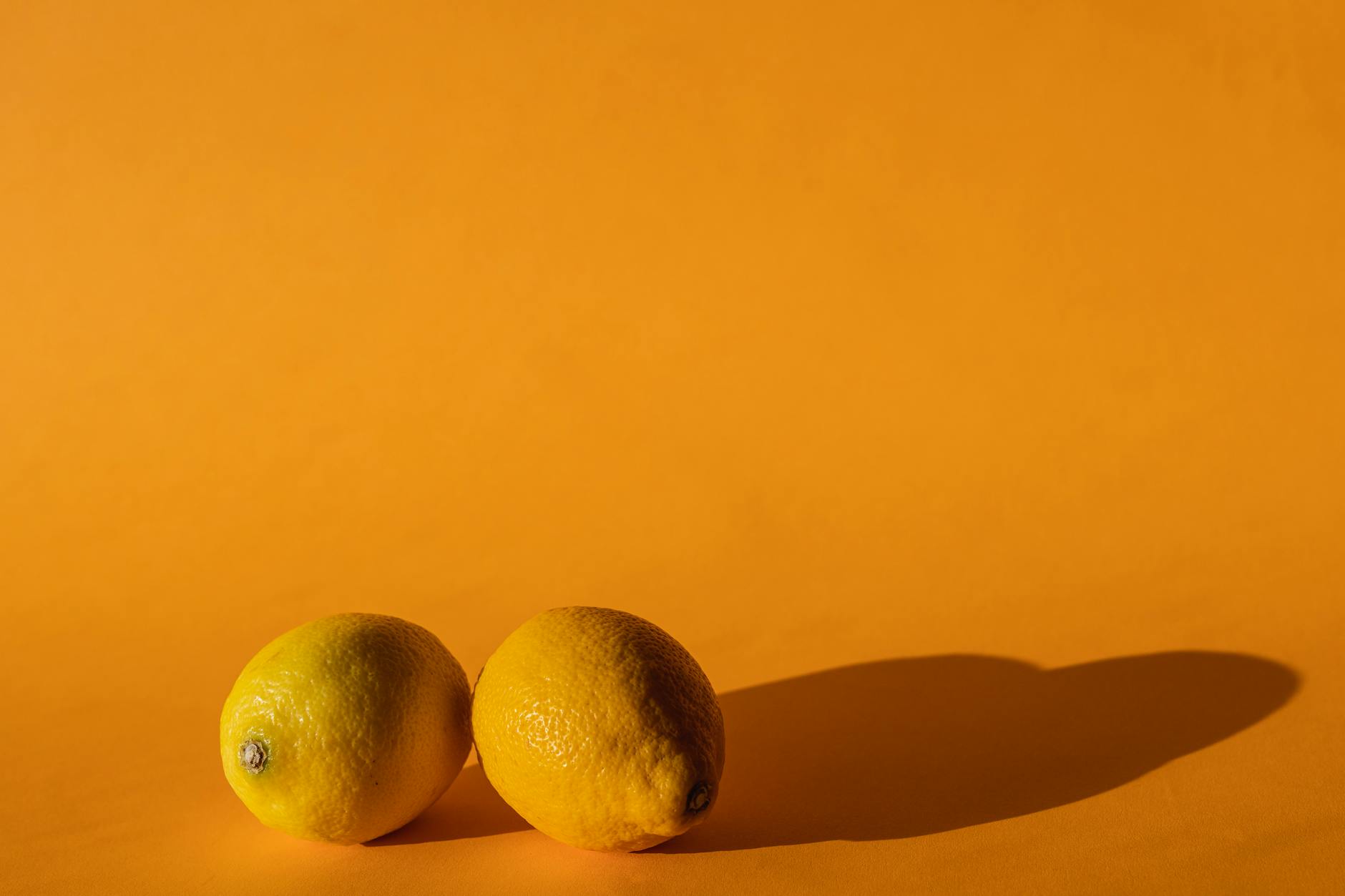 A hand holding an orange vibrator against a minimalistic purple backdrop, showcasing modern sensuality and calm exploration.